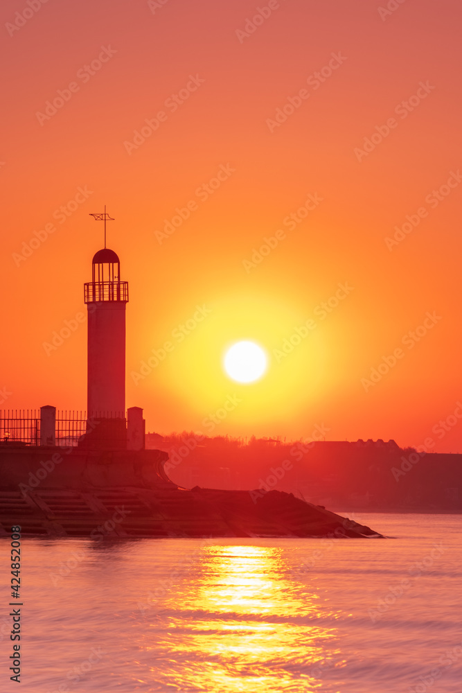 rising sun in the morning and silhouette of lighthouse in orange sky with copy space