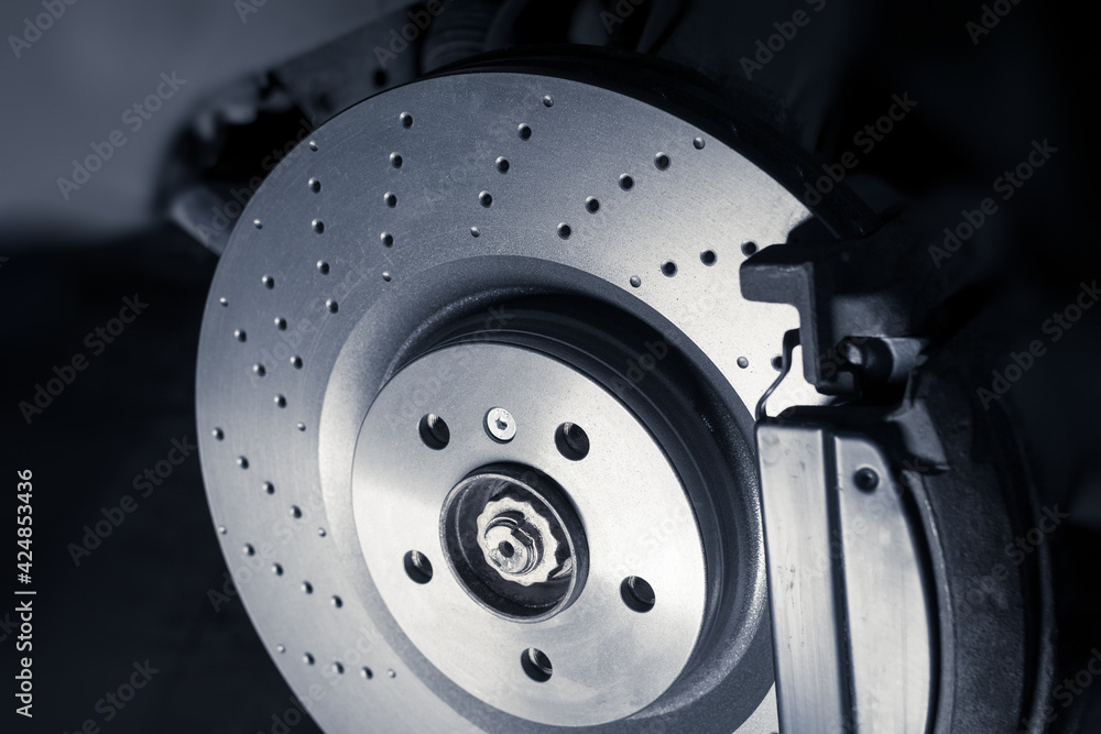 Installation of new perforated brake discs and pads on a modern auto in a car workshop. Blur effect. Installation of new perforated brake discs and pads on a modern auto in a car workshop. Blur effect.