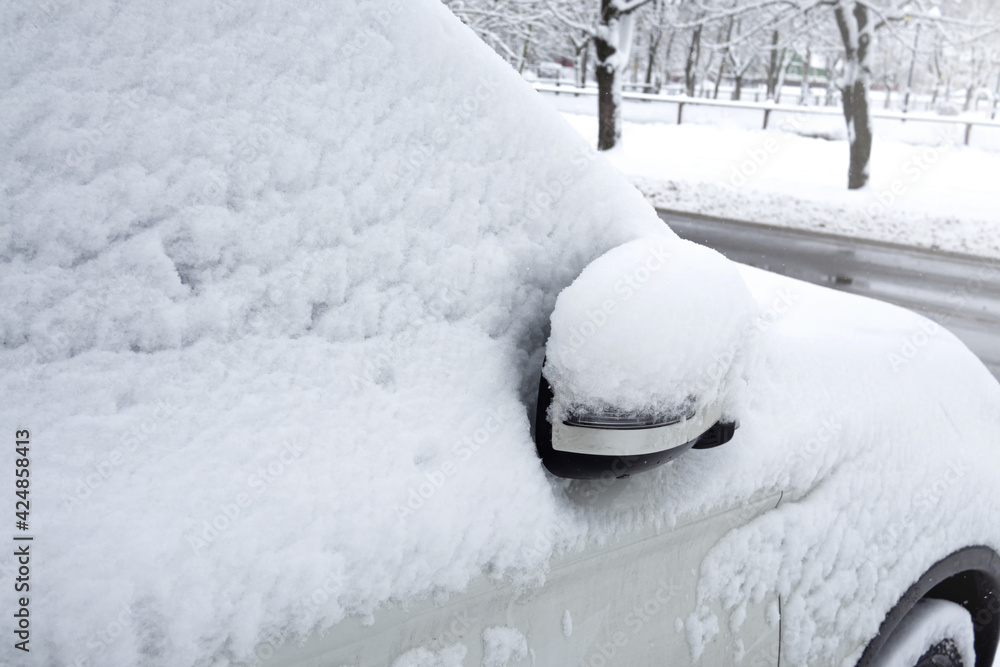 car covered with snow in the winter blizzard in the parking lot