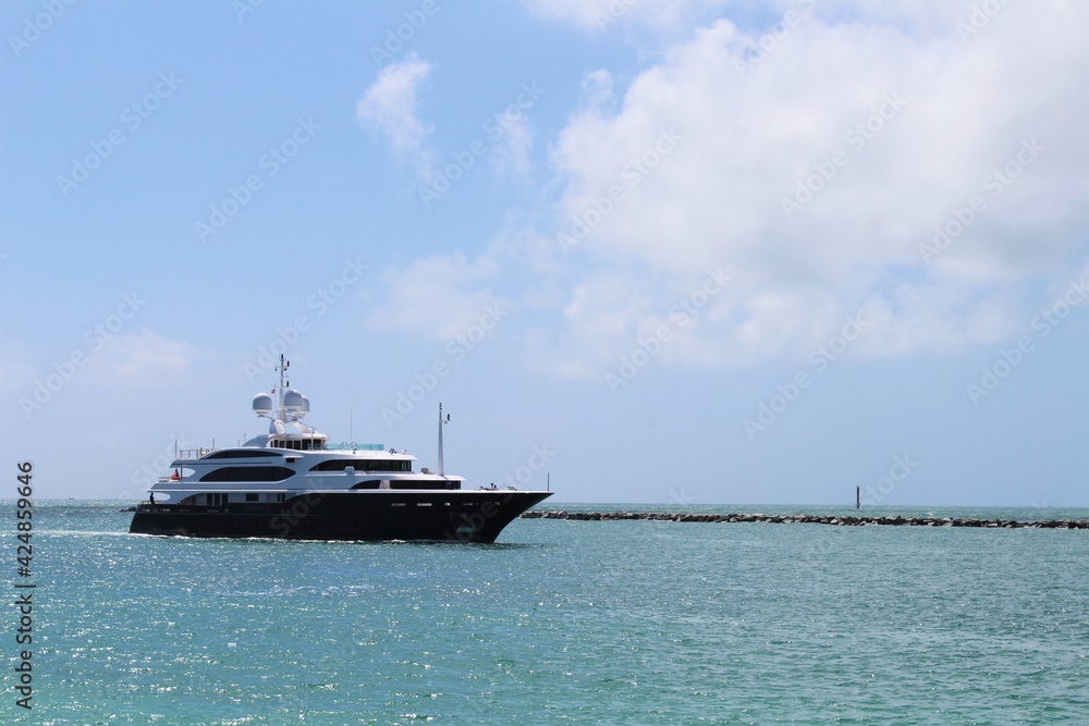Obraz premium Gigantic big and luxurious yacht sailing through Miami Beach, Florida near South Pointe Pier, nearing the port. Copyspace Advertising. Investment for millionaires. Faces blurred out