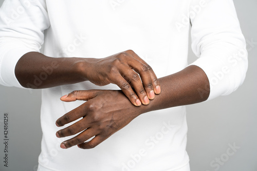 Photography Closeup of African man arms touching painful wrist caused by prolonged work on computer, laptop