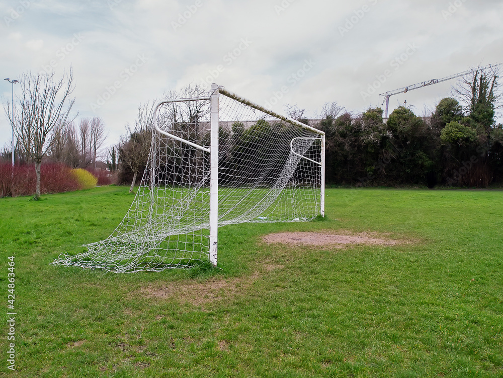 Fototapeta premium Football goal post on a training ground. Worn out grass on a keeper spot. Soccer theme background
