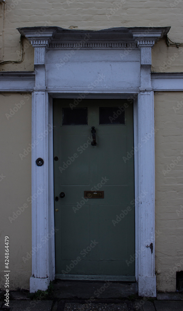 Green and white door in a yellow and old house at Winchester, England