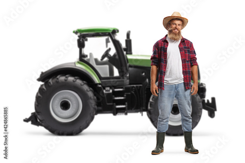 Young bearded farmer posing in front of a tractor