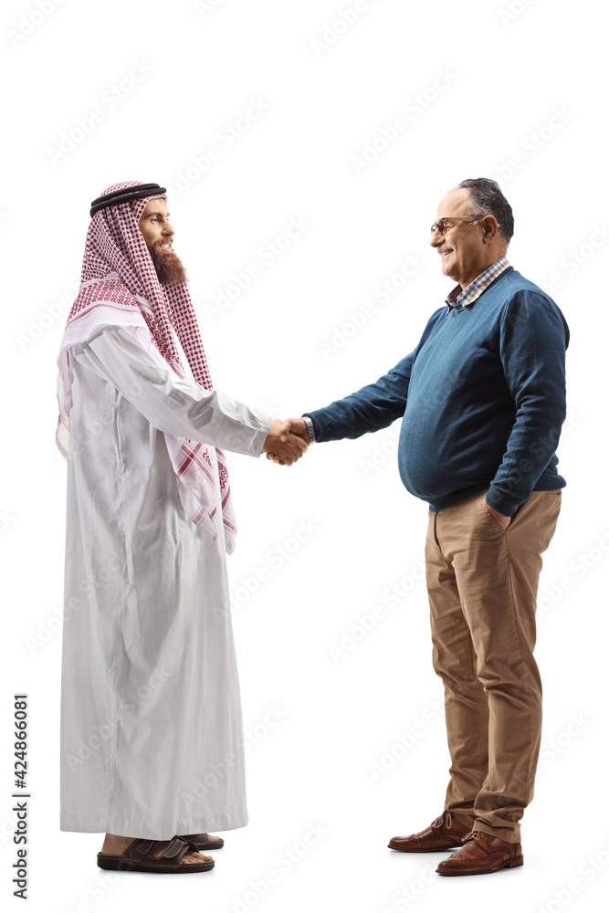 Full length profile shot of a young saudi arab man shaking hands with a mature man Full length profile shot of a young saudi arab man shaking hands with a mature man