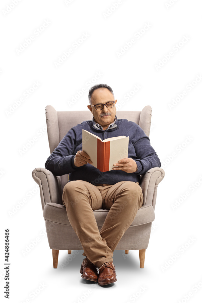 Mature man sitting in an armchair and reading a book