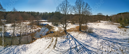 Obraz na płótnie Early spring landscape with melting snow and thawed patches in meadow. Forest and Isloch creek in sunny march w salonie