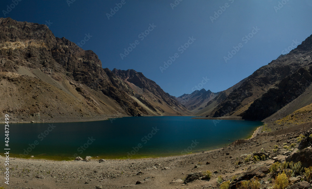 Panorama view of the popular Inca lagoon in the Andes mountains in Chile. The turquoise glacier water lake very high in the cordillera, surrounded by rocky mountains and the arid desert.