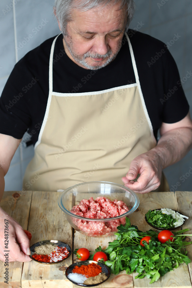 Man chef loads spices into a bowl of minced meat. Cooking minced meat for cutlets, hamburger or kebab.