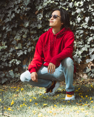 Gen z man sitting on the ground with hoodie red