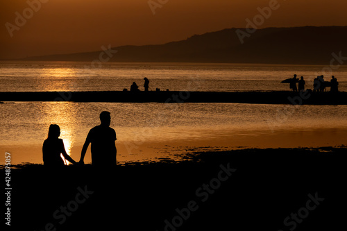 Silhouettes of people backlit in a stunning sunset on a beach in Tarifa, Spain.