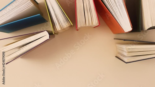 Vintage old books half opened appear on beige background with copy space. Stop motion flat lay