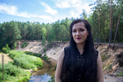 A girl stands by a stream in the forest flowing through a ravine