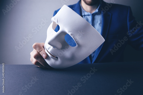 фотографія Businessman holding white mask in his hand