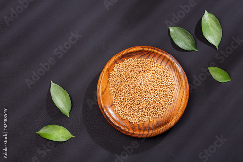 Fotografie Sinapis alba - Organic yellow mustard seeds in the wooden bowl