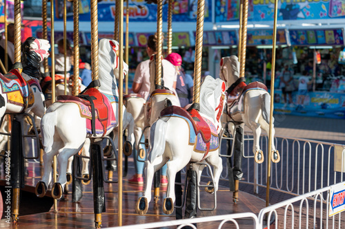 kids at an amusement park rides a horse on a carousel in the summer