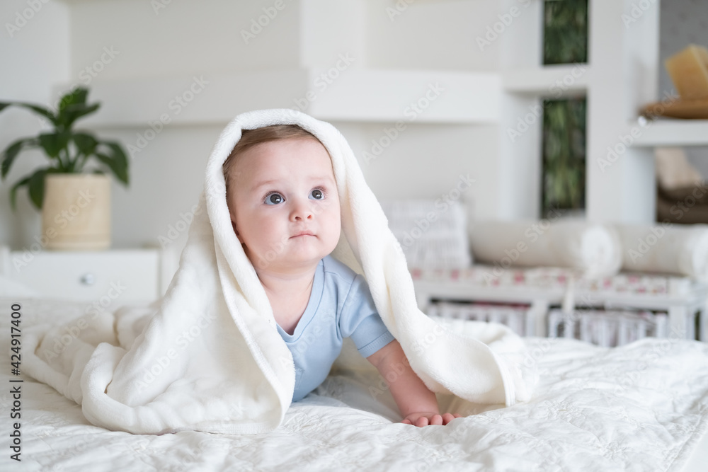 cute baby boy 6 months old in blu bodysuit smiling and lying on bed with white plaid at home. cute baby boy 6 months old in blu bodysuit smiling and lying on bed with white plaid at home.