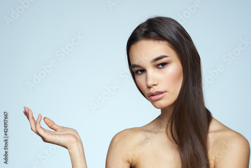 Woman with naked shoulders long hair clean skin cropped view blue background