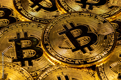 Close-up of gold Bitcoin coins on yellow background.
