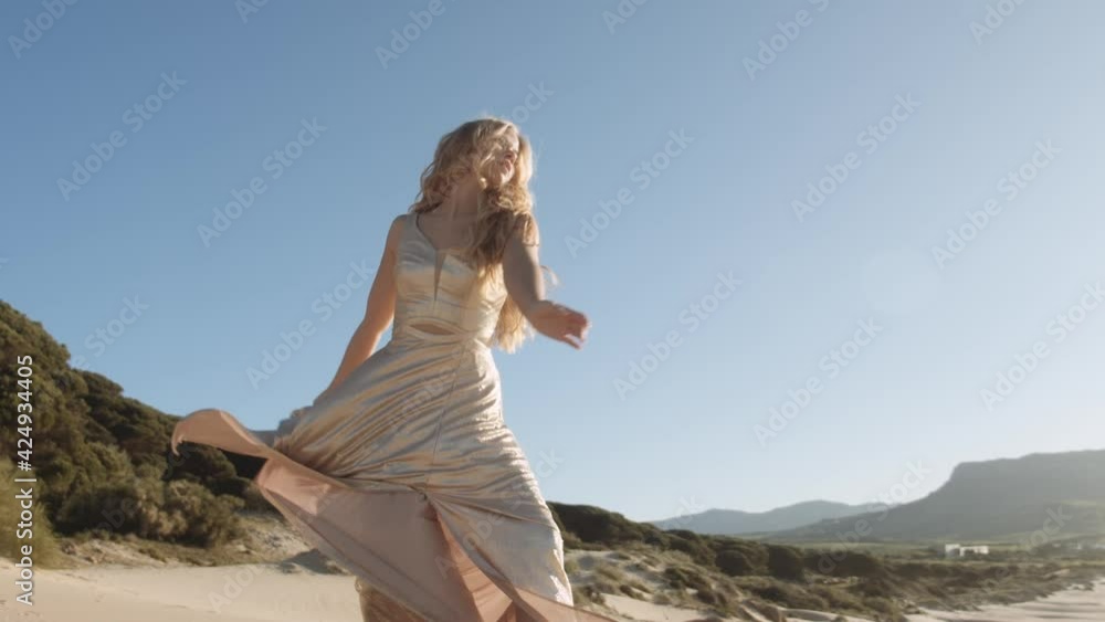 Woman Dancing In Gold Dress Under Blue Sky Woman Dancing In Gold Dress Under Blue Sky