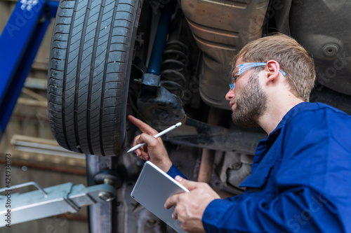 A male auto mechanic in uniform is examining a tire while working in auto service