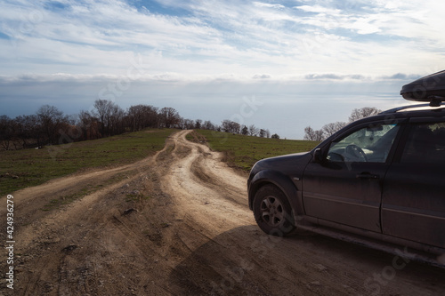 A gravel road leading toward horizon. Spectacular view on the sea and blue sky in the evening. Offroad 4x4 car © Biskariot
