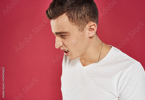 man in white t-shirt close-up red background dissatisfaction