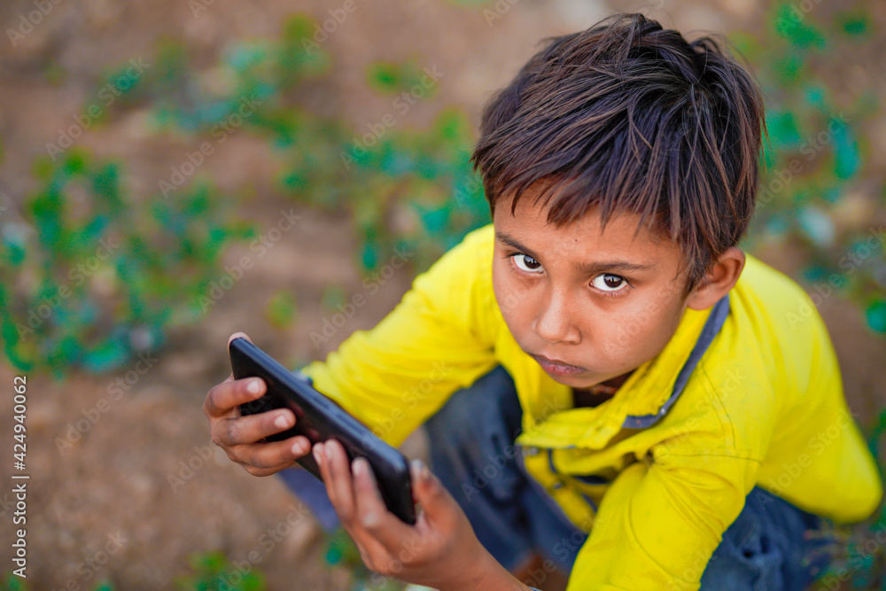Indian poor child playing with mobile at agriculture field. Rural scene. Indian poor child playing with mobile at agriculture field. Rural scene.