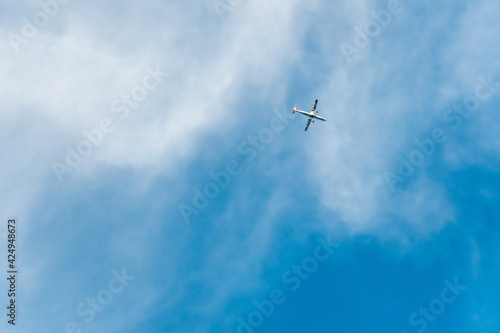 a small silhouette of an airplane in a blue sky with white clouds