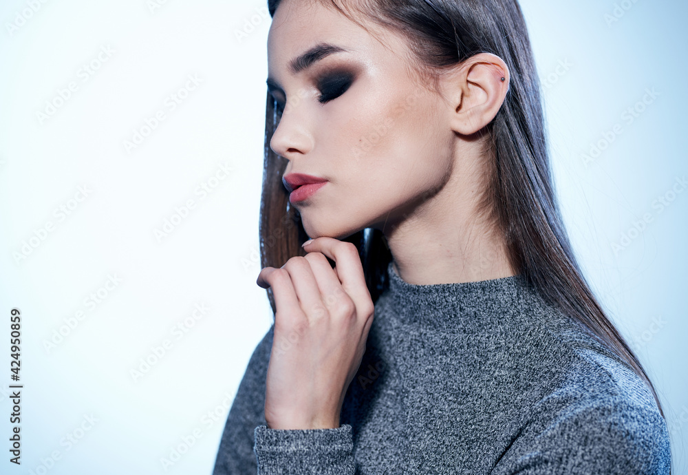Elegant woman in a gray sweater on a light background Makeup on the face Elegant woman in a gray sweater on a light background Makeup on the face