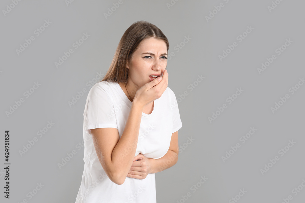 Woman suffering from nausea on grey background, space for text. Food poisoning Woman suffering from nausea on grey background, space for text. Food poisoning