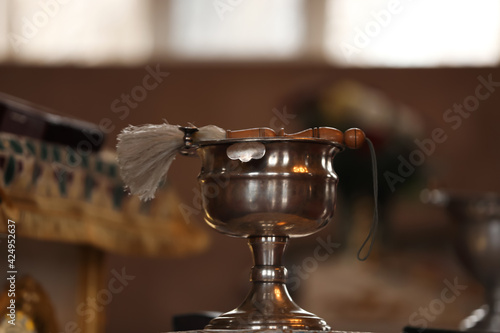Silver vessel with holy water and brush on stand in church. Baptism ceremony