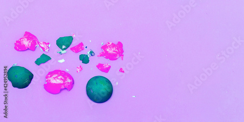 Bright green and dark orange shells on a pastel paper background. Easter background. Happy easter concept. Multicolored decorative eggshell on a blue background.