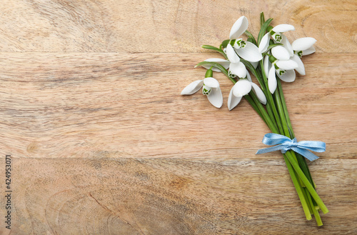 Beautiful snowdrops on wooden table  top view. Space for text