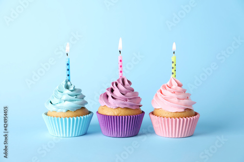 Photography Delicious birthday cupcakes with burning candles on light blue background
