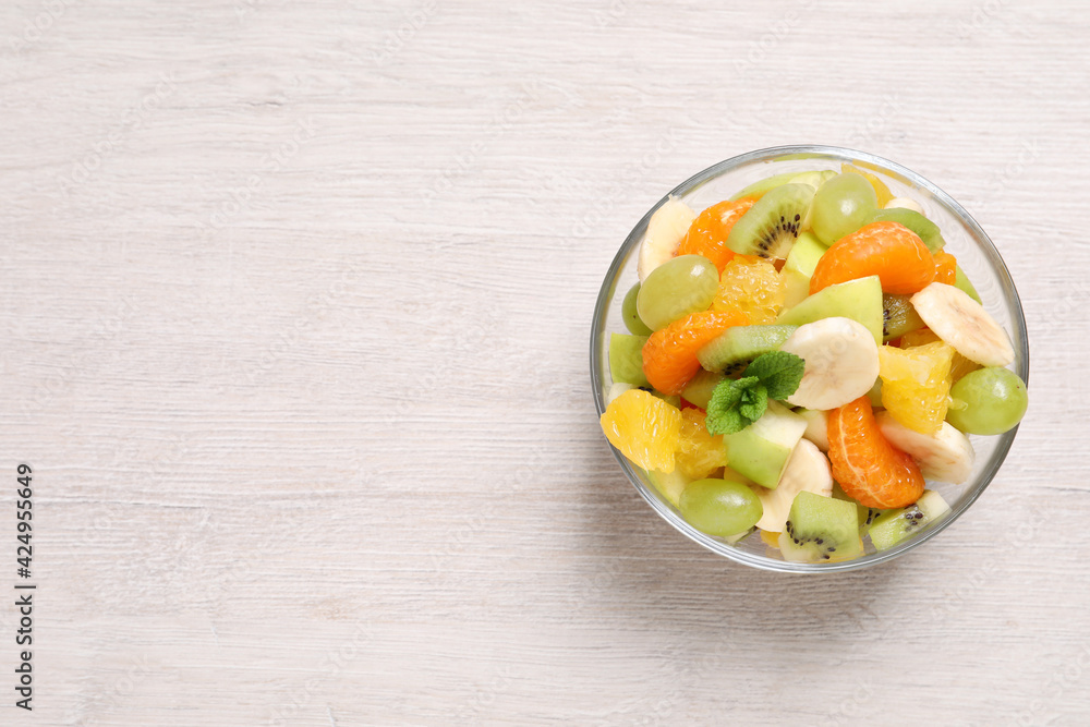 Delicious fresh fruit salad in bowl on white wooden table, top view. Space for text Delicious fresh fruit salad in bowl on white wooden table, top view. Space for text