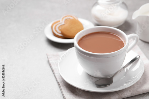 Delicious tea with milk in white cup near cookies on grey table, space for text