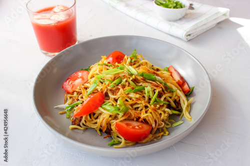 Fried potatoes in straws on a plate with green onions.