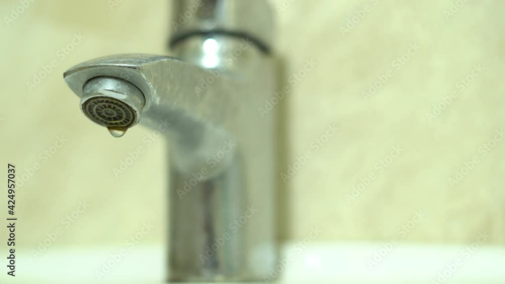 Water dripping from the tap close-up. Scheduled water shutdown and repairs, water saving. Water dripping from the tap close-up. Scheduled water shutdown and repairs, water saving.