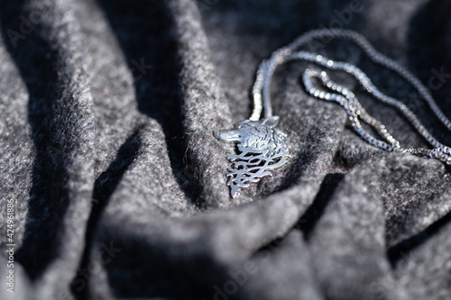 Pendant wolf head necklace silver outside in a summer day closeup. Selective Focus. High quality photo