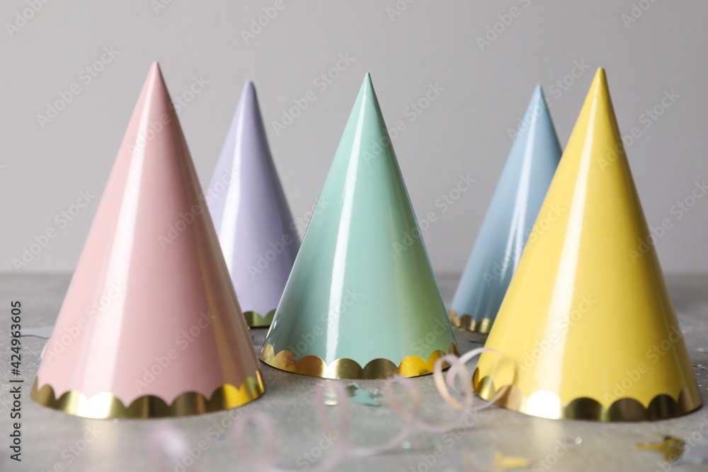 Birthday party hats, serpentine streamers and confetti on grey table Birthday party hats, serpentine streamers and confetti on grey table