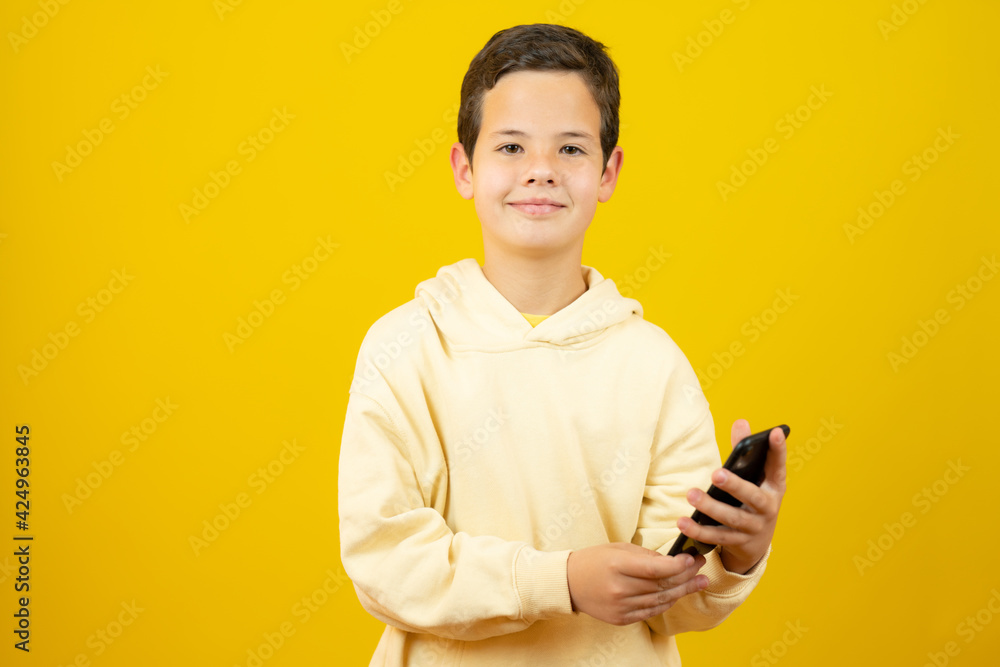 Young caucasian boy with phone isolated over yellow background Young caucasian boy with phone isolated over yellow background