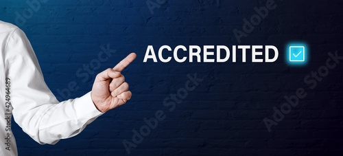 Businessman hand points to the word accredited photo