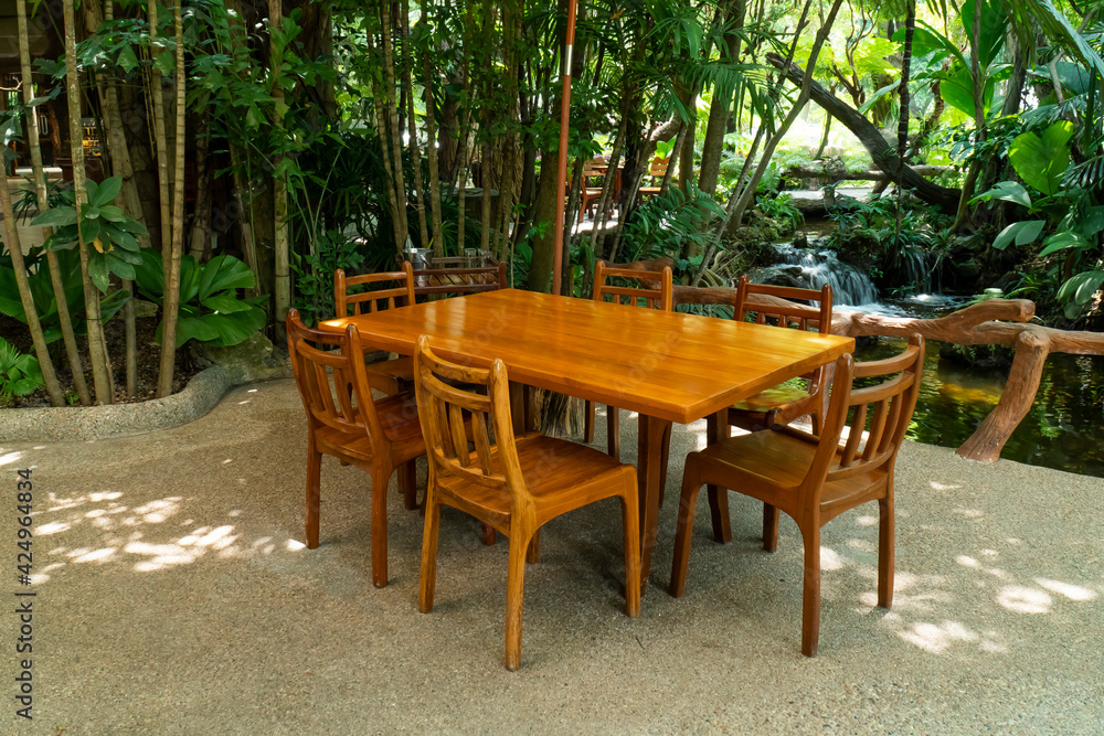 Wood dining table and chair in the restaurant with tree background. Outdoor wooden table and chairs in nature garden