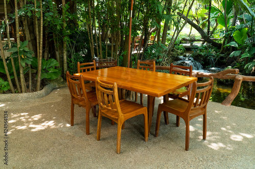 Wood dining table and chair in the restaurant with tree background. Outdoor wooden table and chairs in nature garden