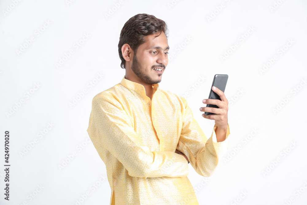 Young indian man in tradition wear and using smartphone on white background. Young indian man in tradition wear and using smartphone on white background.