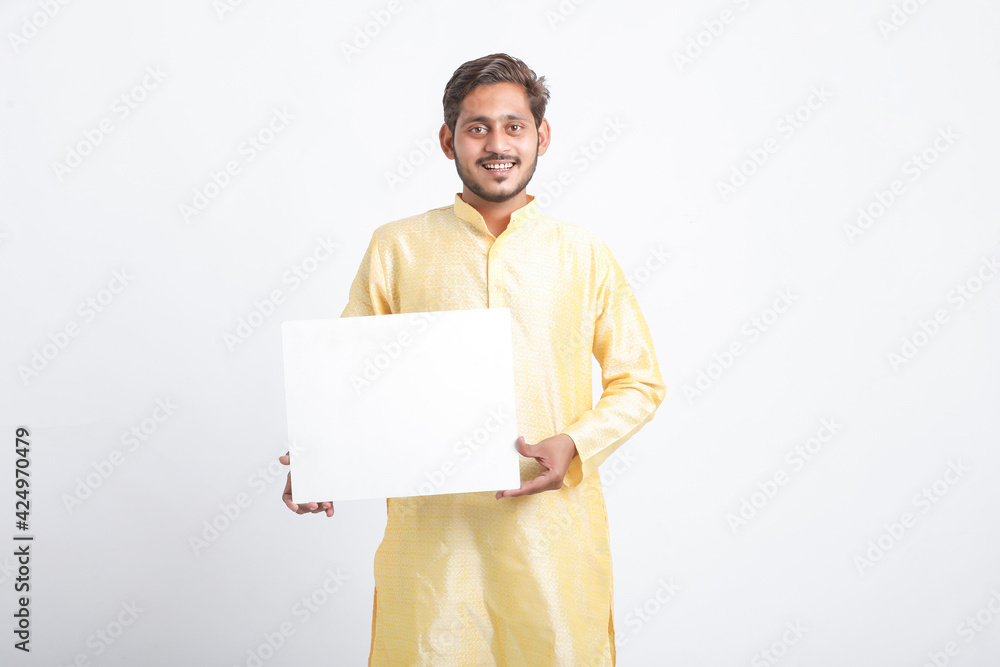 Indian man holding white board, promoting offers on festival season while wearing traditional cloths, standing over white background. Indian man holding white board, promoting offers on festival season while wearing traditional cloths, standing over white background.