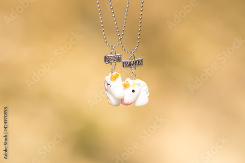 Pendant set of best friends two unicorns necklace shoot outside in a summer day closeup. Selective Focus. High quality photo
