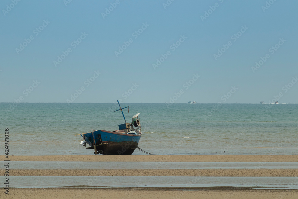 fisherman's fishing boat on sand at a fishing village beach There is an island and sea background with the daytime sky.  stranded fishing boat After the sea has receded