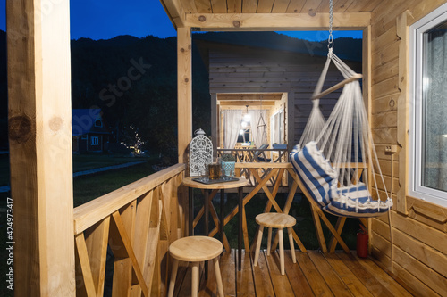 Porch terrace in wooden rustic house with hanging chair, table and chairs